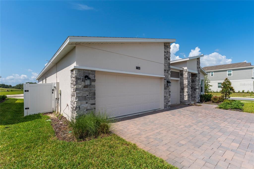A single-story house with a stone-accented facade, a two-car garage, and a paved driveway — 1744 RIDER RAIN LANE, APOPKA, FL