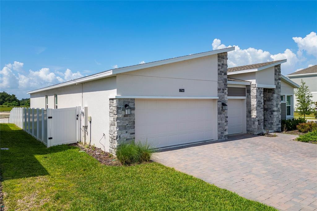 A single-story house with a stone-accented facade, a two-car garage, and a white fence — 1744 RIDER RAIN LANE, APOPKA, FL