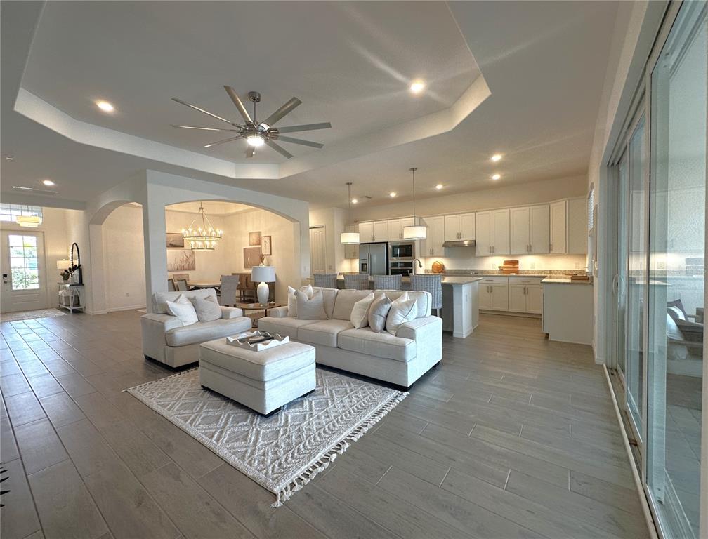 An open-concept living room and kitchen feature light wood-look tile flooring and white cabinetry — 14897 CHERRY BLOSSOM WAY, PUNTA GORDA, FL