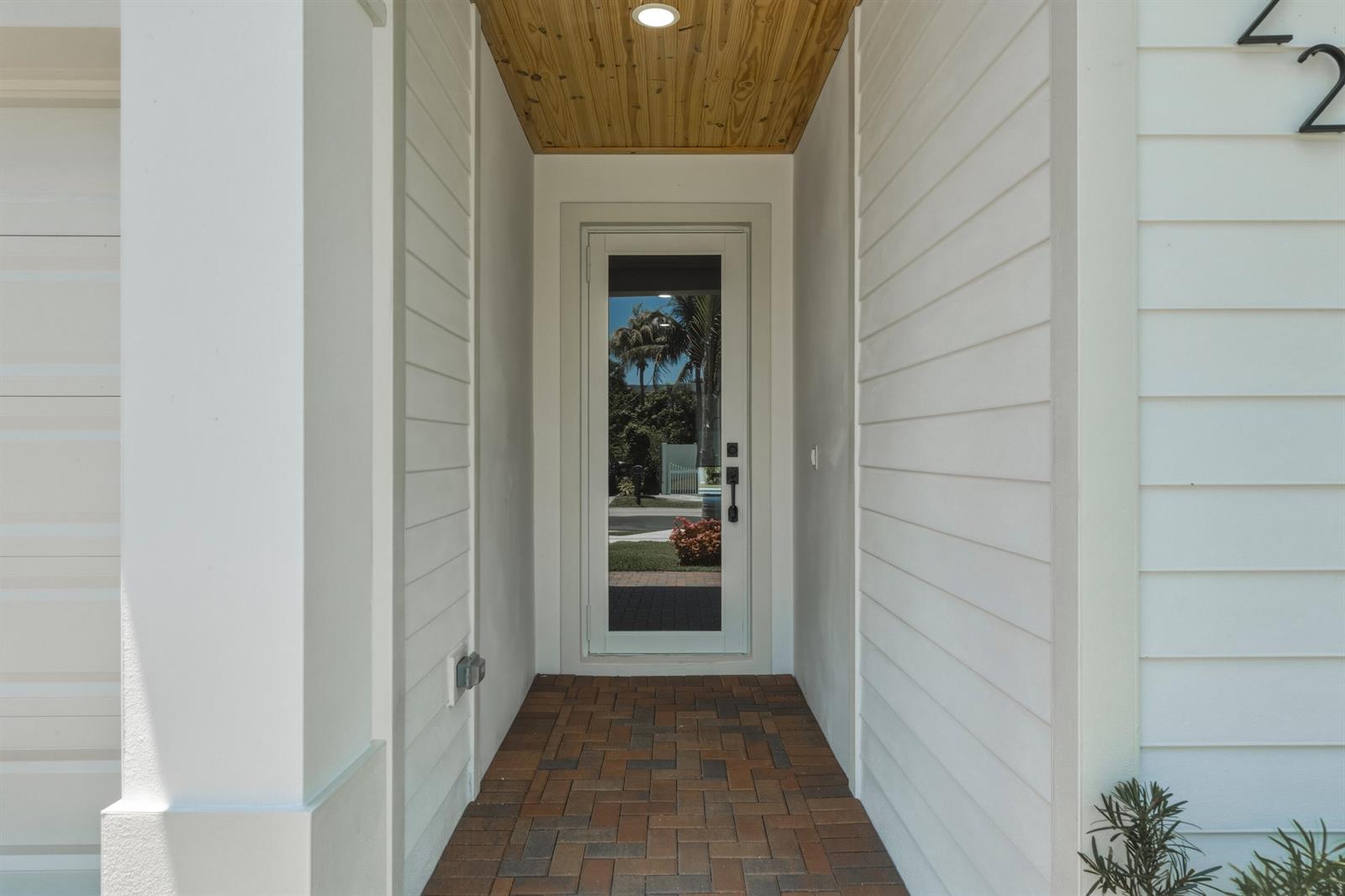 A covered entryway features white horizontal siding, a wood-paneled ceiling, and brick paver flooring — 1022 Miami Boulevard, Delray Beach FL 33483, DELRAY BEACH, FL