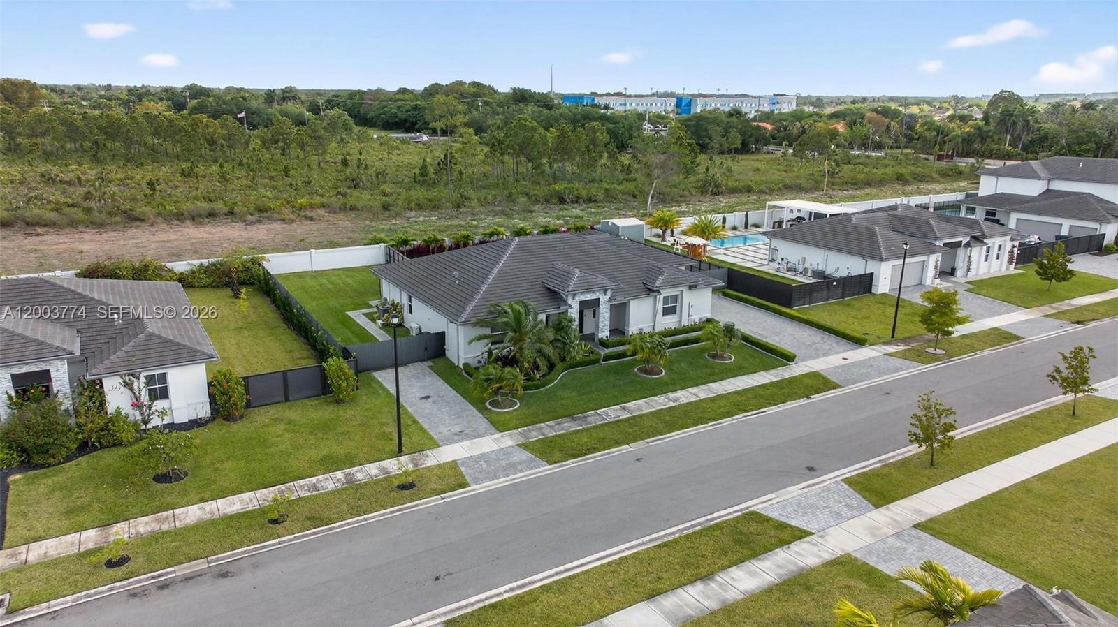An aerial view shows a single-story suburban house with a gray roof and pool — HOMESTEAD, FL