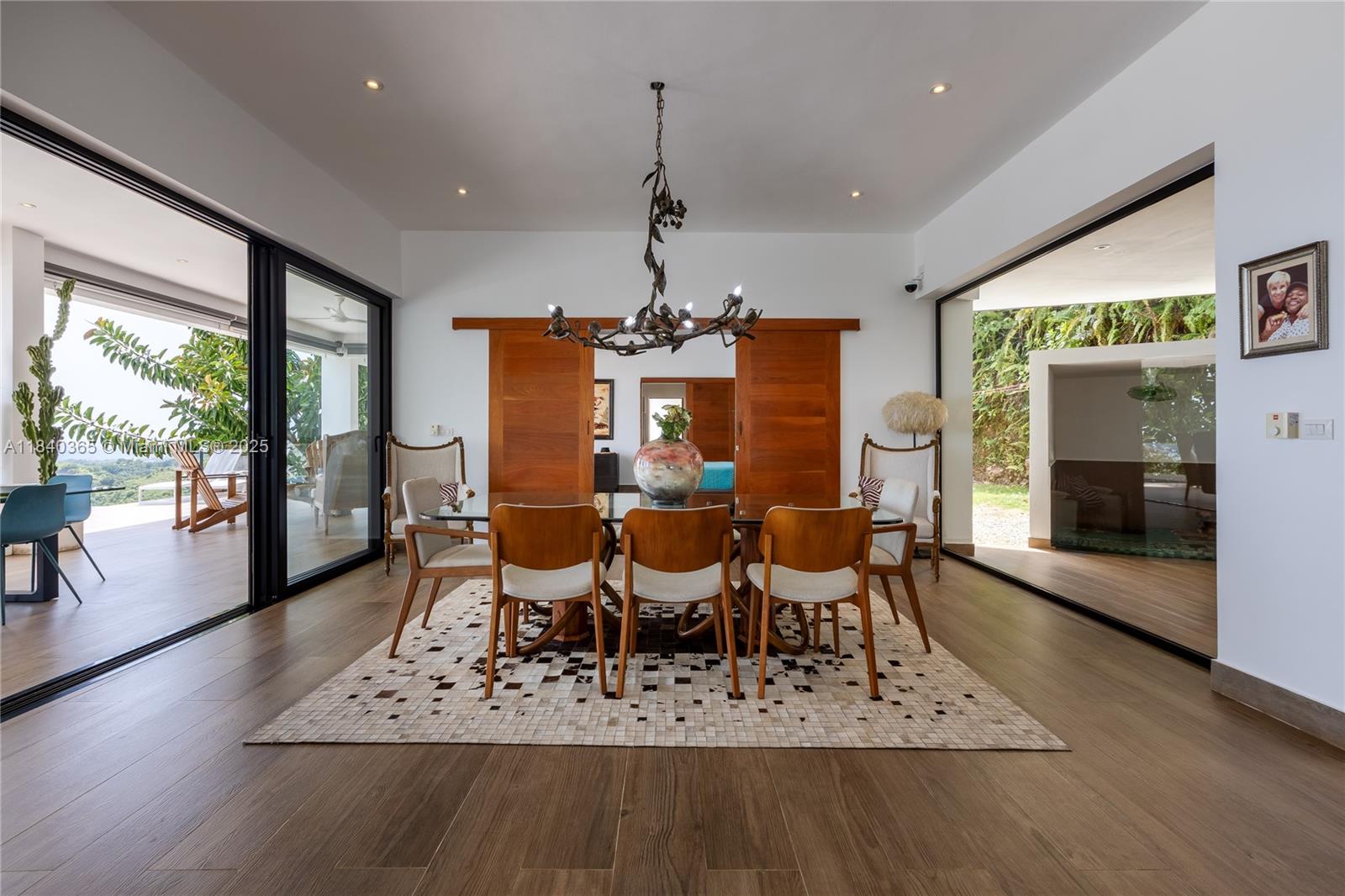 A dining room features a glass table, wooden chairs, a chandelier, and large sliding glass doors — Palmar de los Nidos LAS TERRENAS, SAMANA, FL 32000, FL