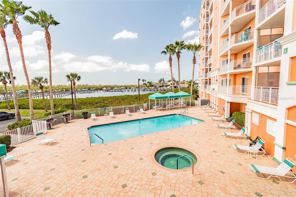 An outdoor swimming pool and hot tub are situated on a patio beside a building — 4516 SEAGULL DRIVE UNIT 416, NEW PORT RICHEY, FL