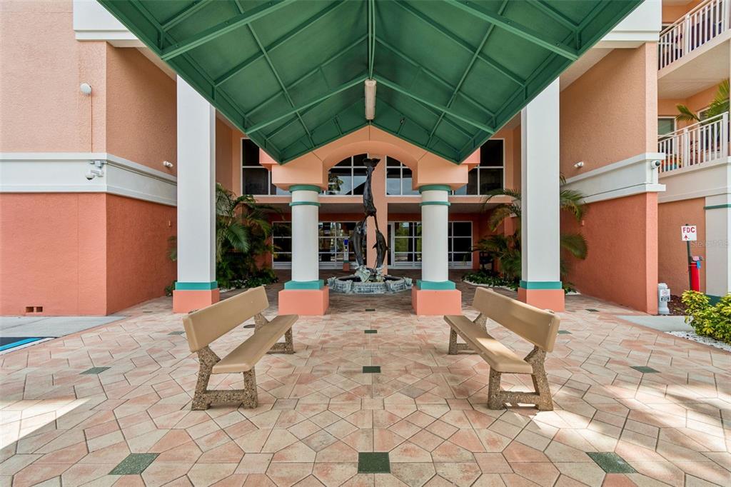An outdoor entrance features a green metal awning, two benches, and a dolphin fountain — 4516 SEAGULL DRIVE UNIT 416, NEW PORT RICHEY, FL