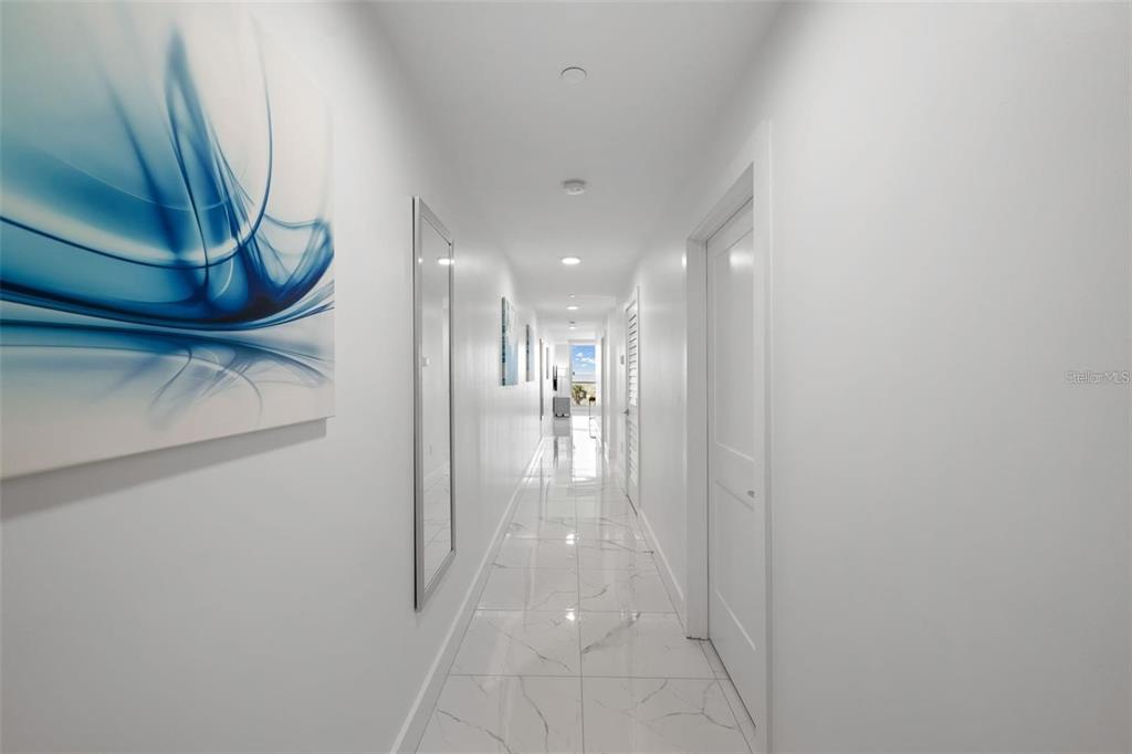 A long, narrow hallway features white walls, marble-patterned tile flooring, and recessed ceiling lighting — 11500 GULF BOULEVARD UNIT 304, TREASURE ISLAND, FL