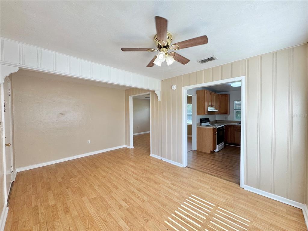 A living room with wood-look flooring, a ceiling fan, and doorways leading to other rooms — 921 AVENUE E NE, WINTER HAVEN, FL