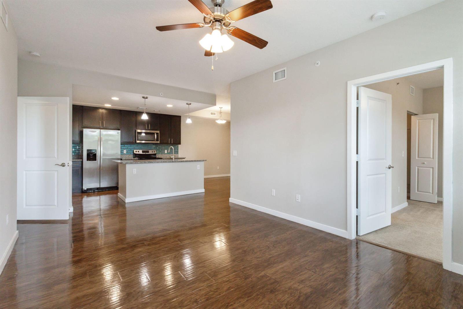 An open-concept living area with wood-look flooring, a ceiling fan, and an adjacent kitchen — 3615 High Ridge Road # 201, Boynton Beach FL 33426, BOYNTON BEACH, FL