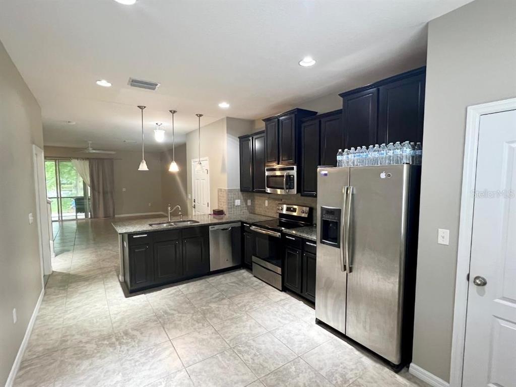 A kitchen features dark wood cabinets, stainless steel appliances, and tile flooring — 13801 RIVER FISH CT, TAMPA, FL