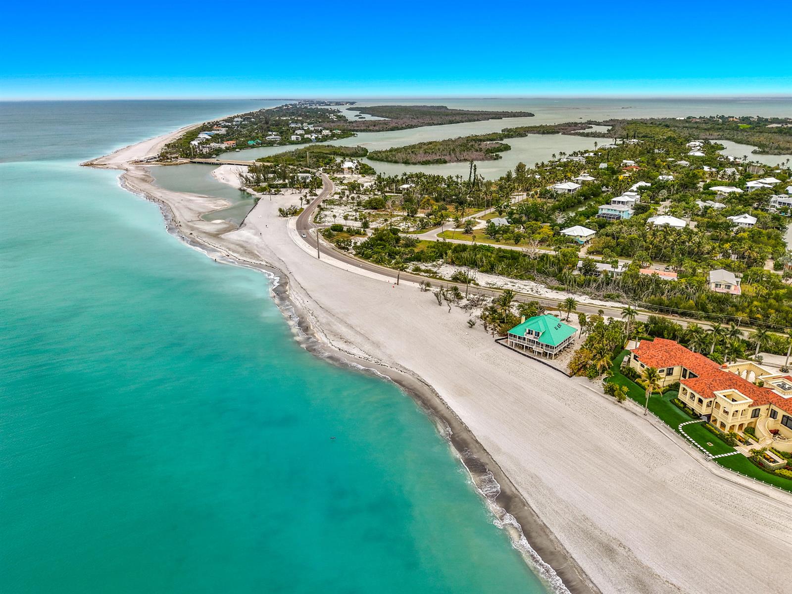 An aerial view shows a sandy beach, turquoise water, and coastal homes along a road — 6351 Sanibel Captiva Road, FL 33957, FL