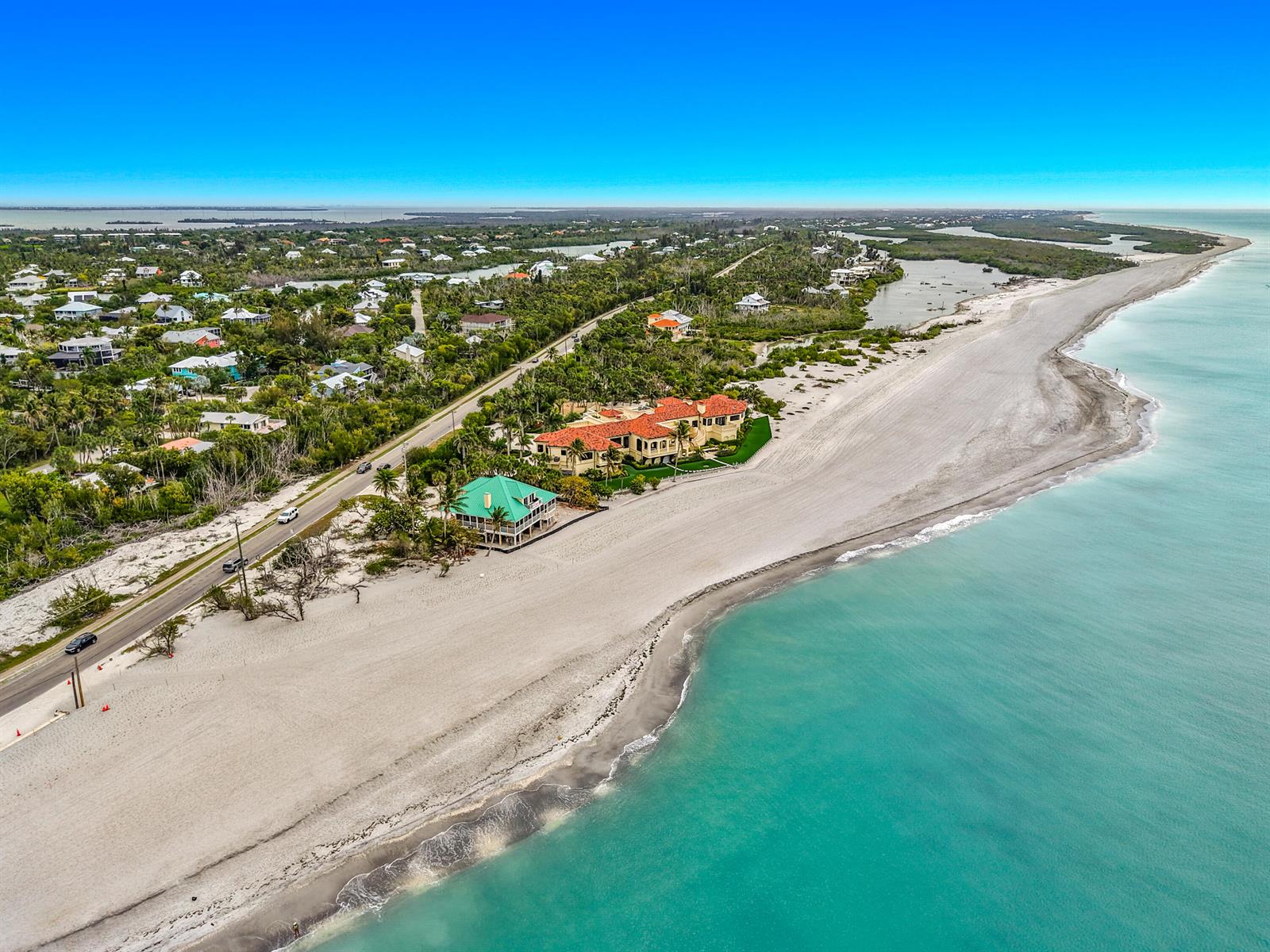 An aerial view shows a coastal road, beachfront houses, and turquoise water along the shore — 6351 Sanibel Captiva Road, FL 33957, FL
