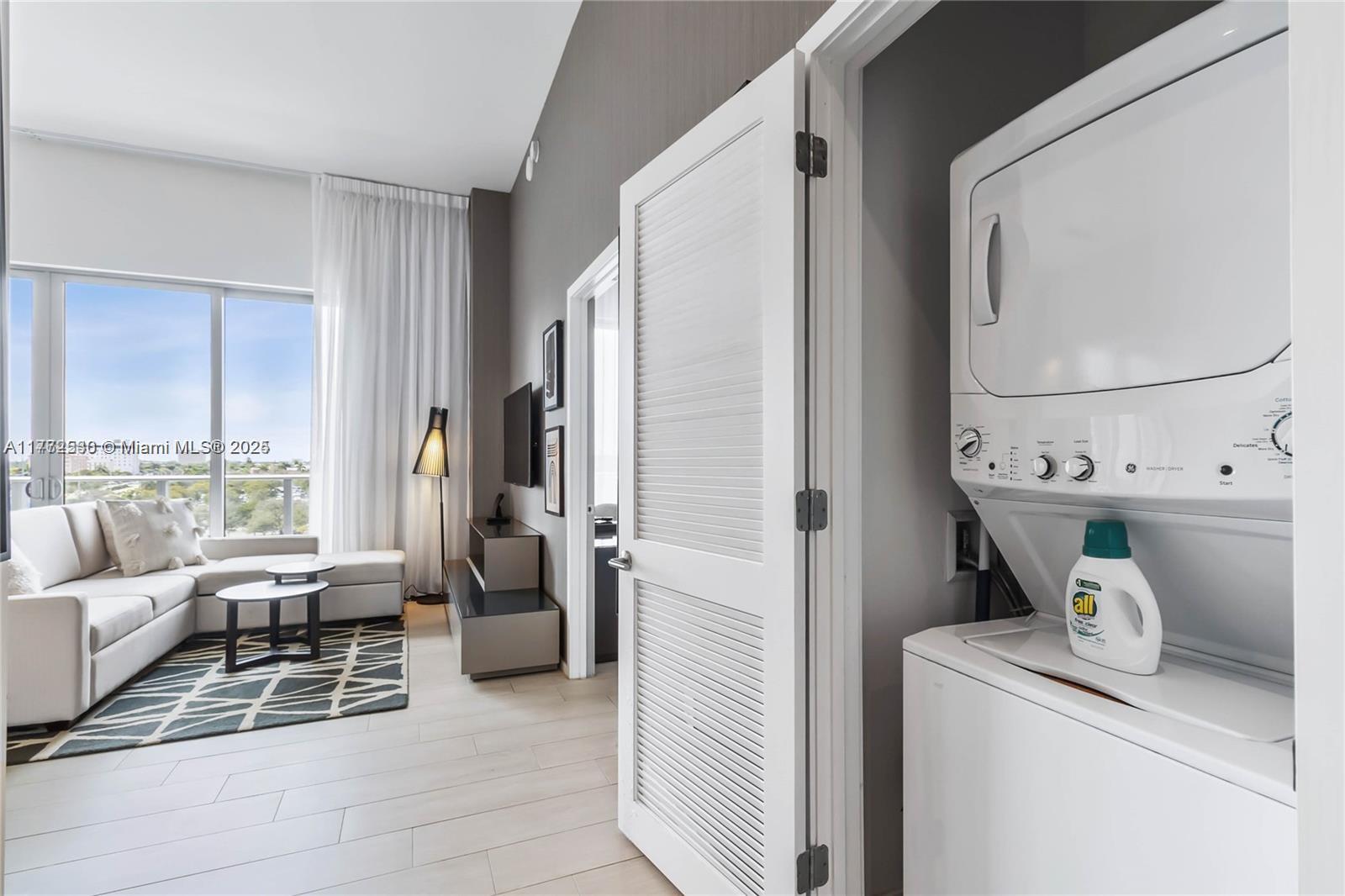 A living room with a sectional sofa and a laundry closet with a stacked washer-dryer — 4010 S Ocean Dr # R406, Hollywood FL 33019, HOLLYWOOD, FL