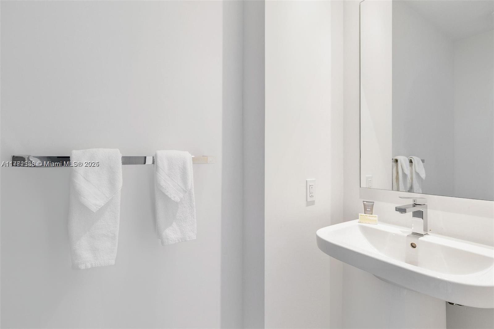 A minimalist bathroom features a wall-mounted white sink, a chrome faucet, and two hanging towels — 4010 S Ocean Dr # R406, Hollywood FL 33019, HOLLYWOOD, FL