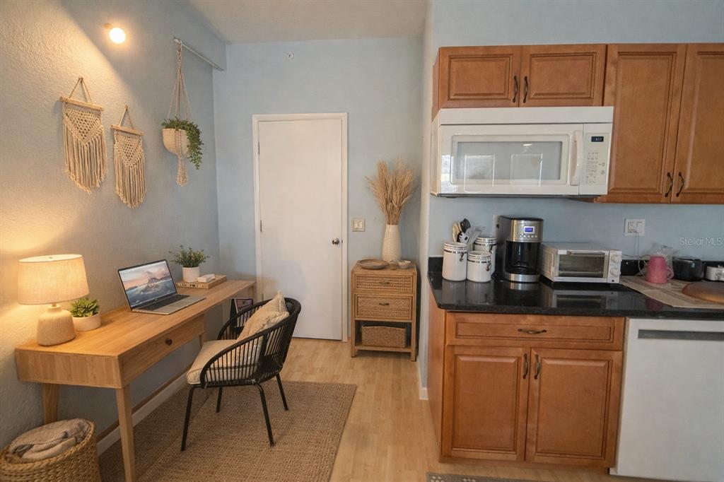 A kitchen area features wooden cabinets, a desk workspace, and a white door — 101 PALM HARBOR PARKWAY UNIT OC2, PALM COAST, FL