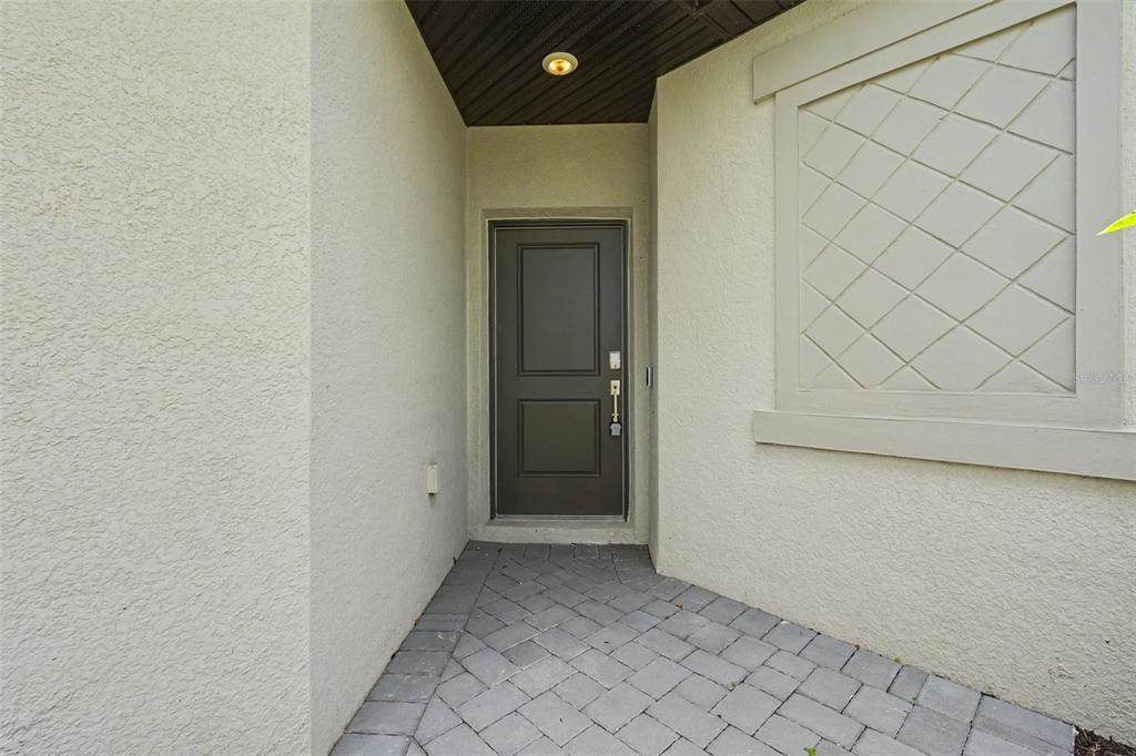 A dark brown front door is set within a recessed entryway with light-colored stucco walls — 15724 SUNNY DAY DRIVE, BRADENTON, FL