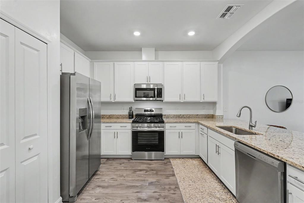 A kitchen with white cabinets, stainless steel appliances, and granite countertops — 15724 SUNNY DAY DRIVE, BRADENTON, FL