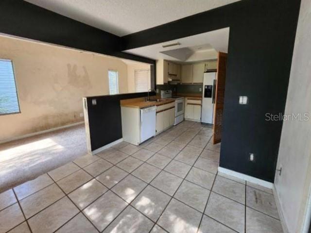 A kitchen with tile flooring, white cabinets, and black accent walls opens to a living area — 270 AMBERWOOD COURT, ORMOND BEACH, FL