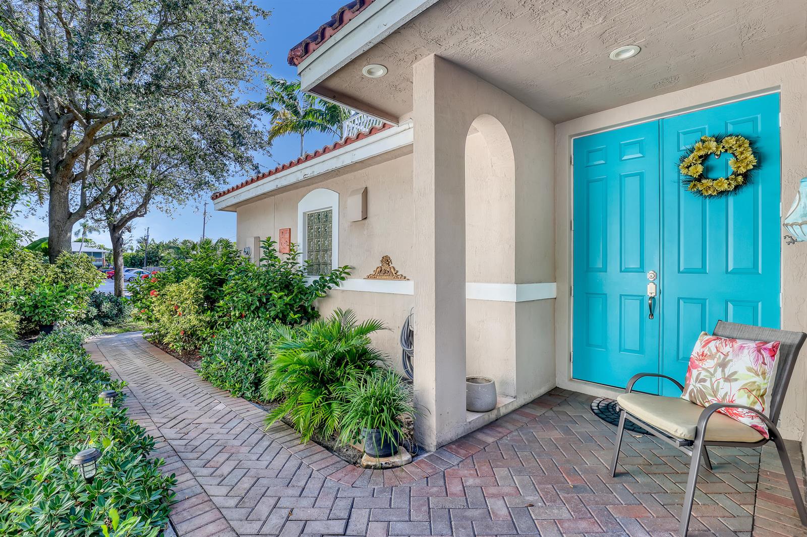 A brick walkway leads to a beige house entrance with bright blue double doors — 2560 NE 11th Street, Pompano Beach FL 33062, POMPANO BEACH, FL