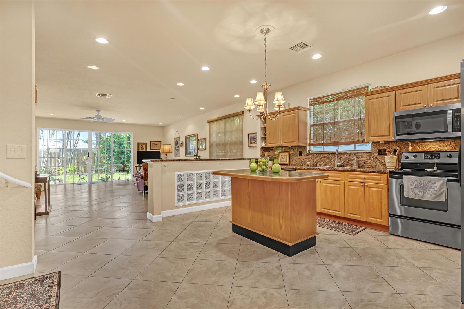 A kitchen with wood cabinets and a center island opens to a living area — 2560 NE 11th Street, Pompano Beach FL 33062, POMPANO BEACH, FL