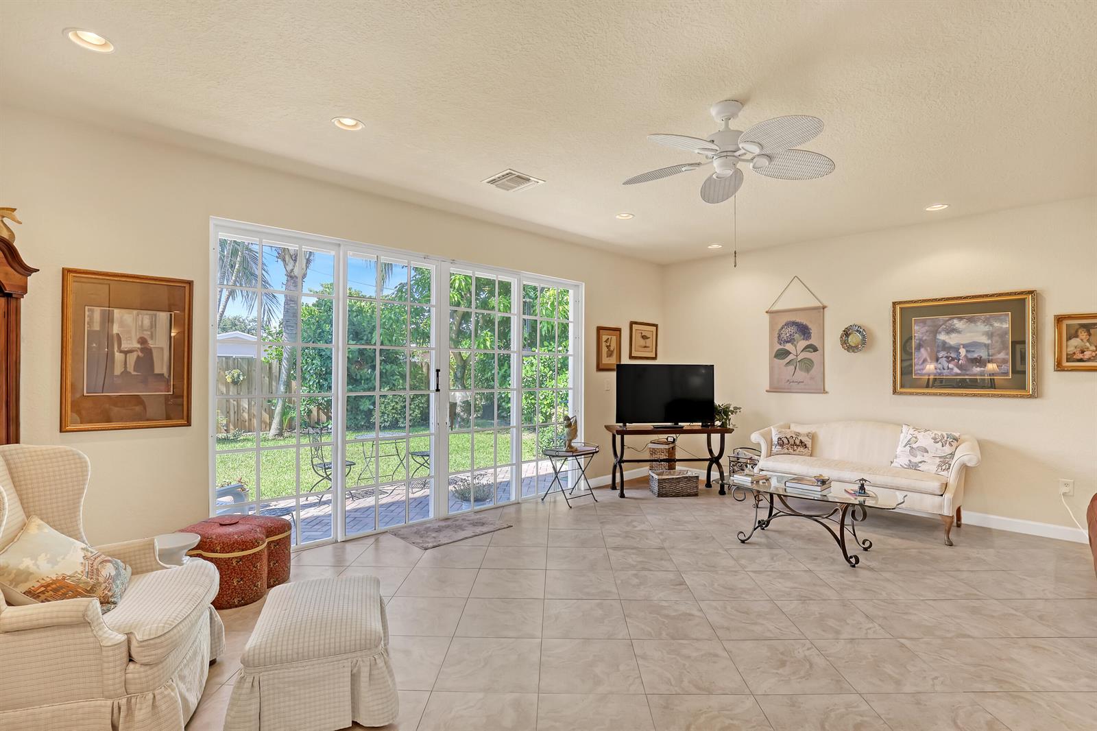 A living room with tile floors, a ceiling fan, and sliding glass doors to a yard — 2560 NE 11th Street, Pompano Beach FL 33062, POMPANO BEACH, FL