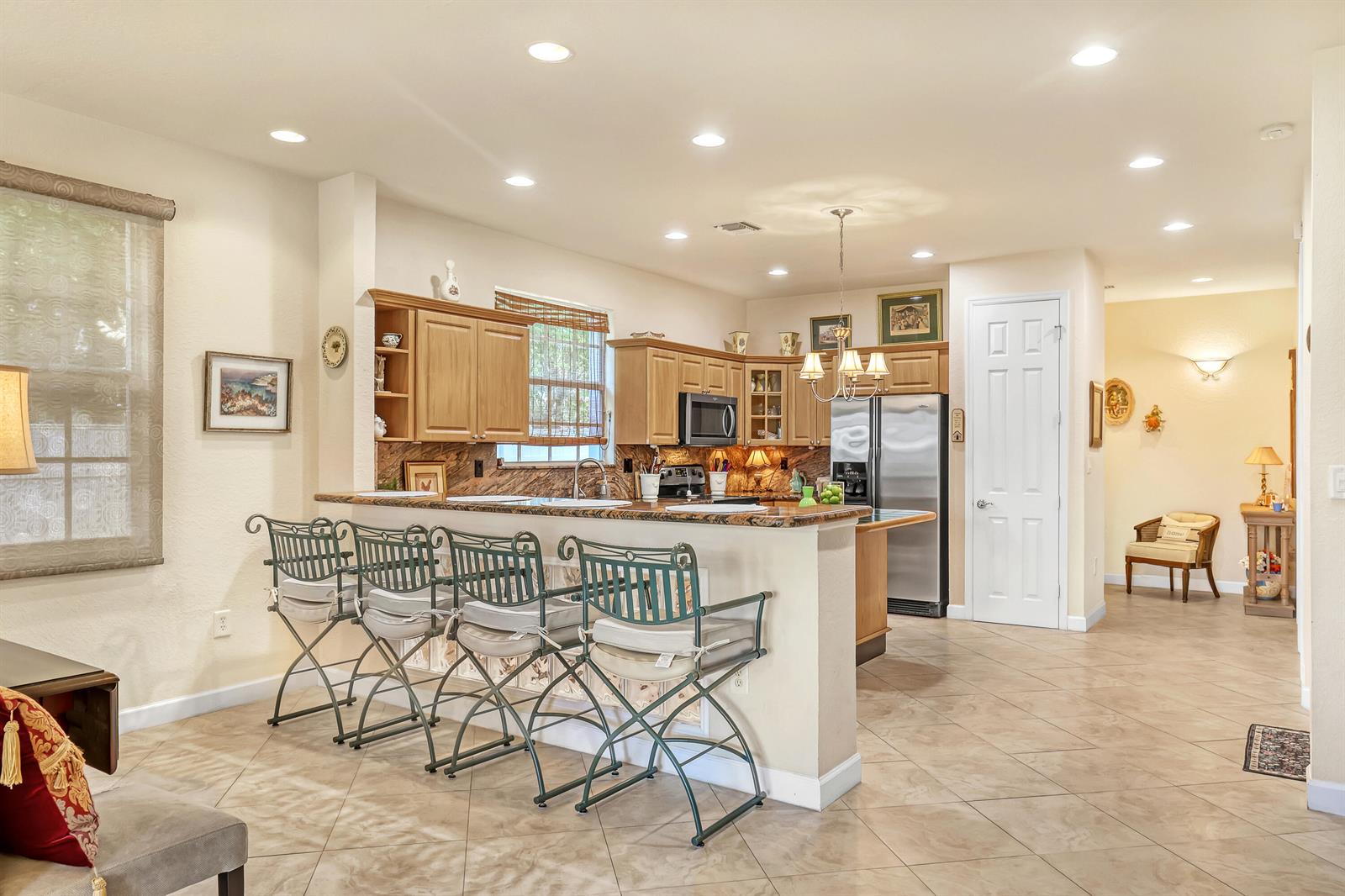 A kitchen features light wood cabinets, granite countertops, a breakfast bar with four chairs, and tile flooring — 2560 NE 11th Street, Pompano Beach FL 33062, POMPANO BEACH, FL