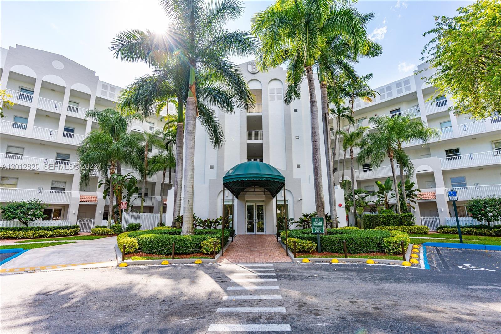 The exterior of a multi-story apartment building features a green awning over the main entrance — 10750 NW 66th St # 408, Doral FL 33178, DORAL, FL