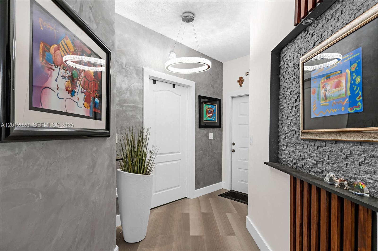 A modern entryway features gray faux-finish walls, a circular light fixture, and framed artwork — 10750 NW 66th St # 408, Doral FL 33178, DORAL, FL