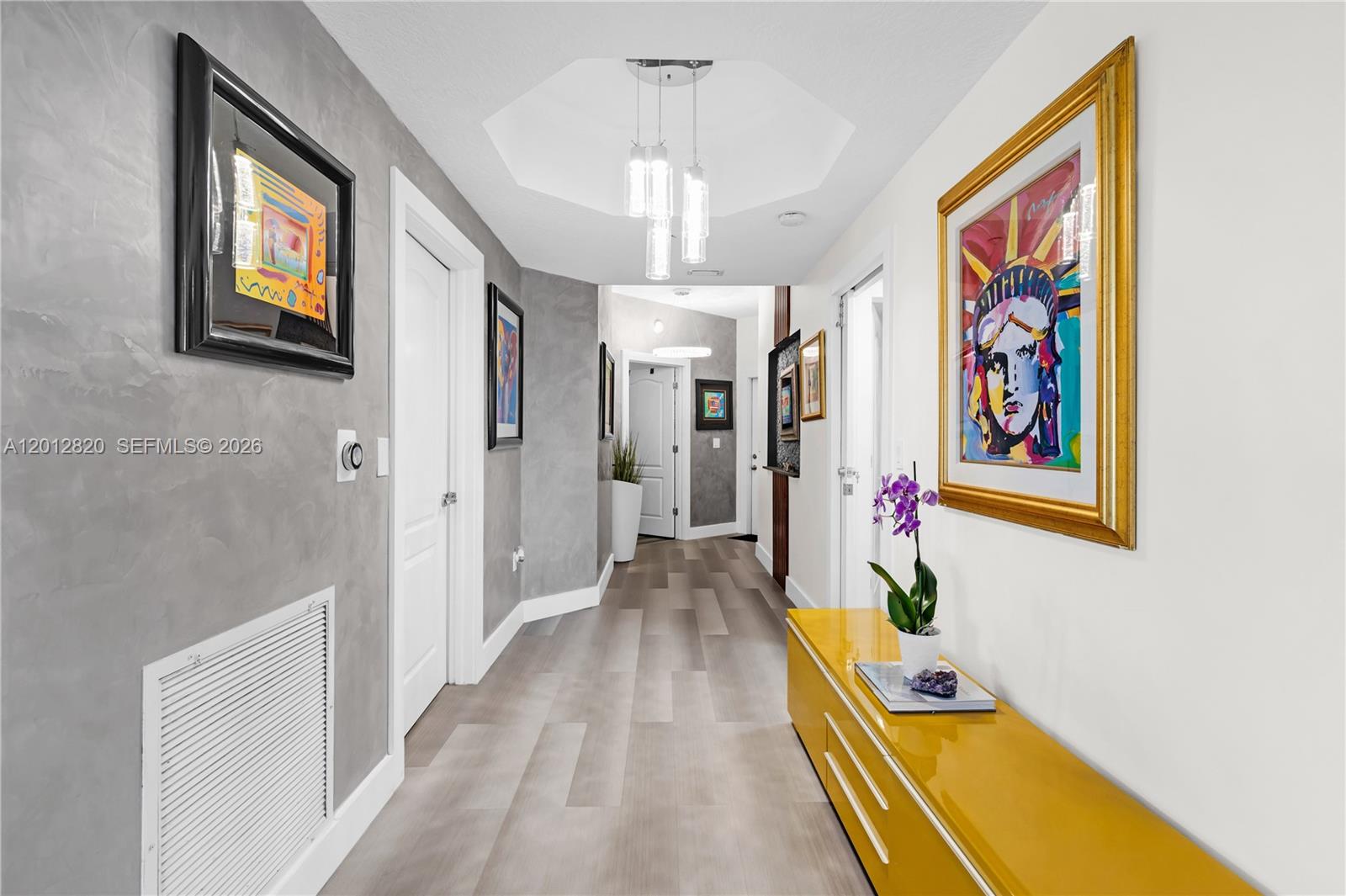 A hallway features gray textured walls, wood-look flooring, a yellow console table, and artwork — 10750 NW 66th St # 408, Doral FL 33178, DORAL, FL