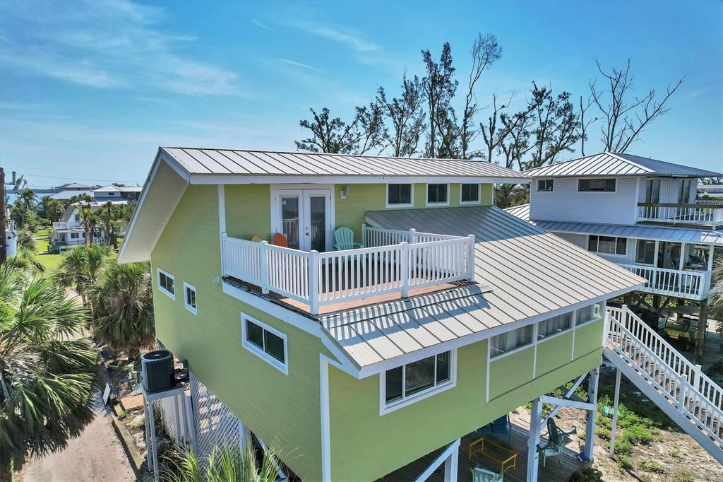 An elevated lime green house with a metal roof and a second-story balcony — 9350 LITTLE GASPARILLA ISLAND, PLACIDA, FL