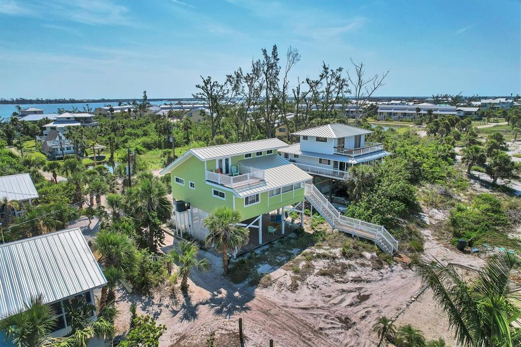An aerial view of two elevated houses with metal roofs surrounded by trees and sand — 9350 LITTLE GASPARILLA ISLAND, PLACIDA, FL