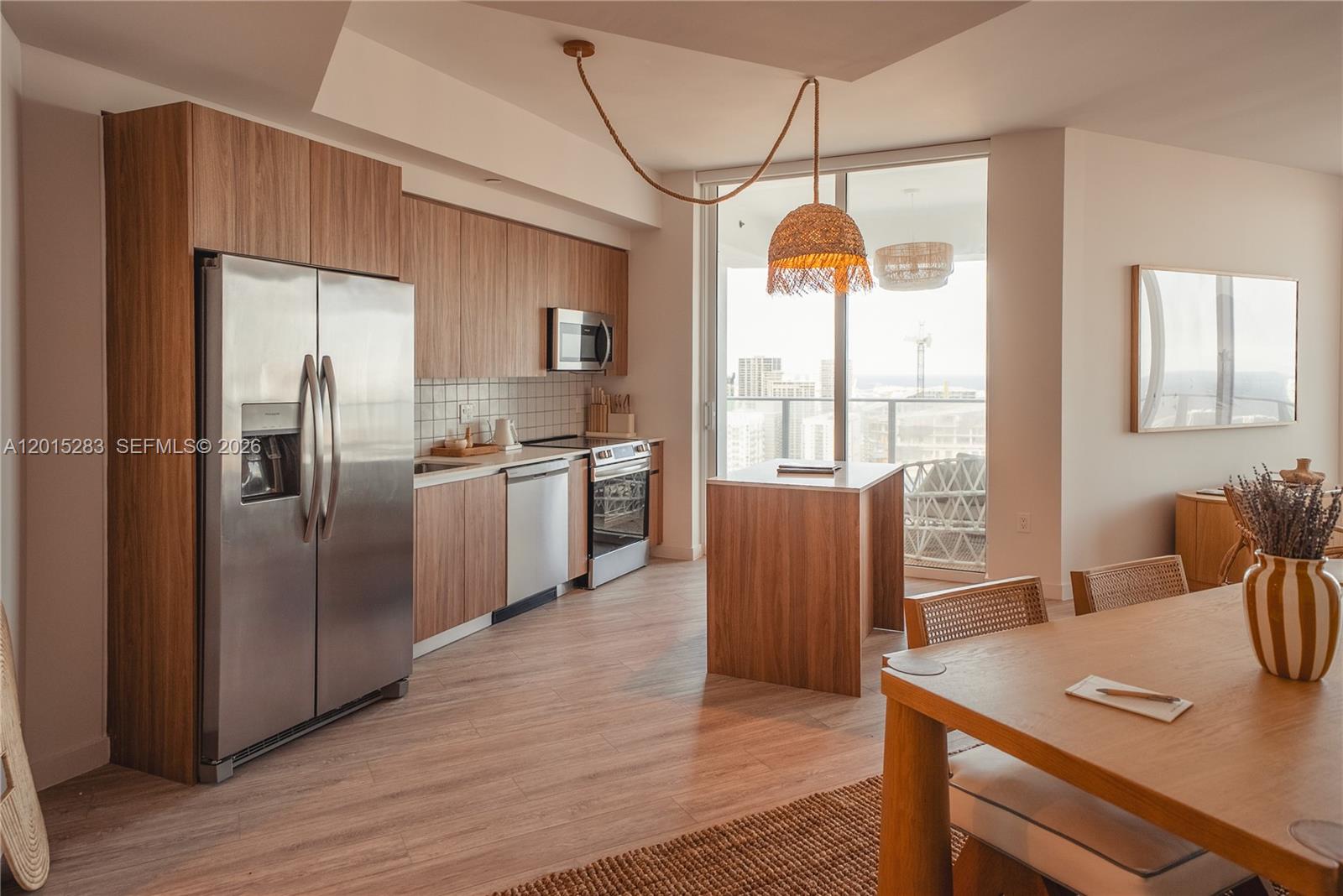 A modern kitchen features wood-grain cabinetry, stainless steel appliances, and a small central island — 275 SW 6th St # 5308, Miami FL 33130, MIAMI, FL