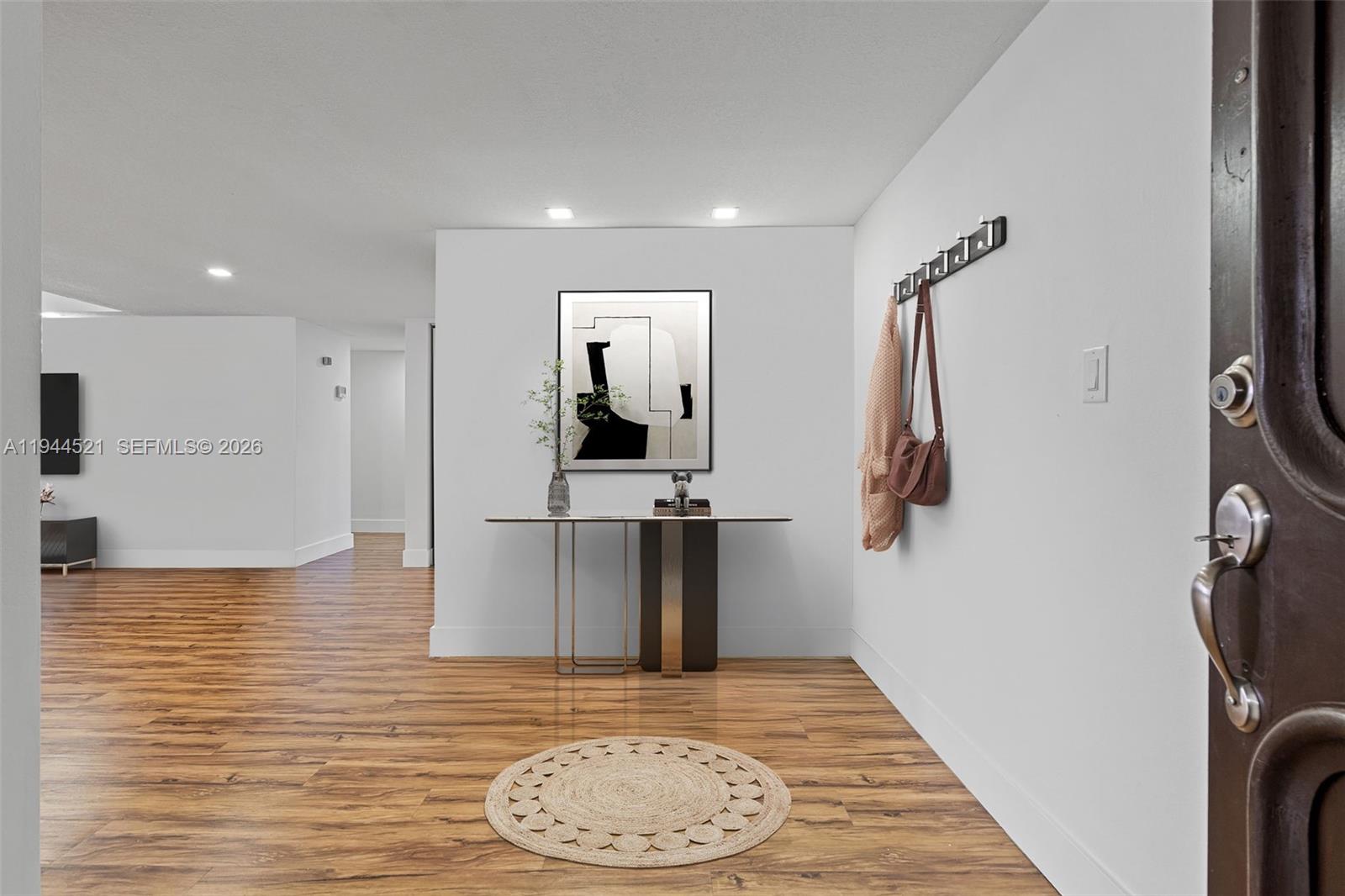 An entryway features a console table, wall art, a coat rack, and wood-look flooring — 13953 Kendale Lakes Cir # 608B, Miami FL 33183, MIAMI, FL