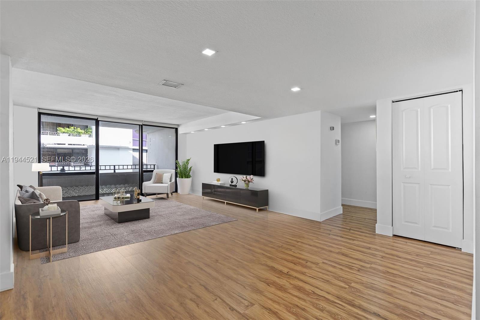 A living room features wood-look flooring, a wall-mounted television, and a sliding glass balcony door — 13953 Kendale Lakes Cir # 608B, Miami FL 33183, MIAMI, FL