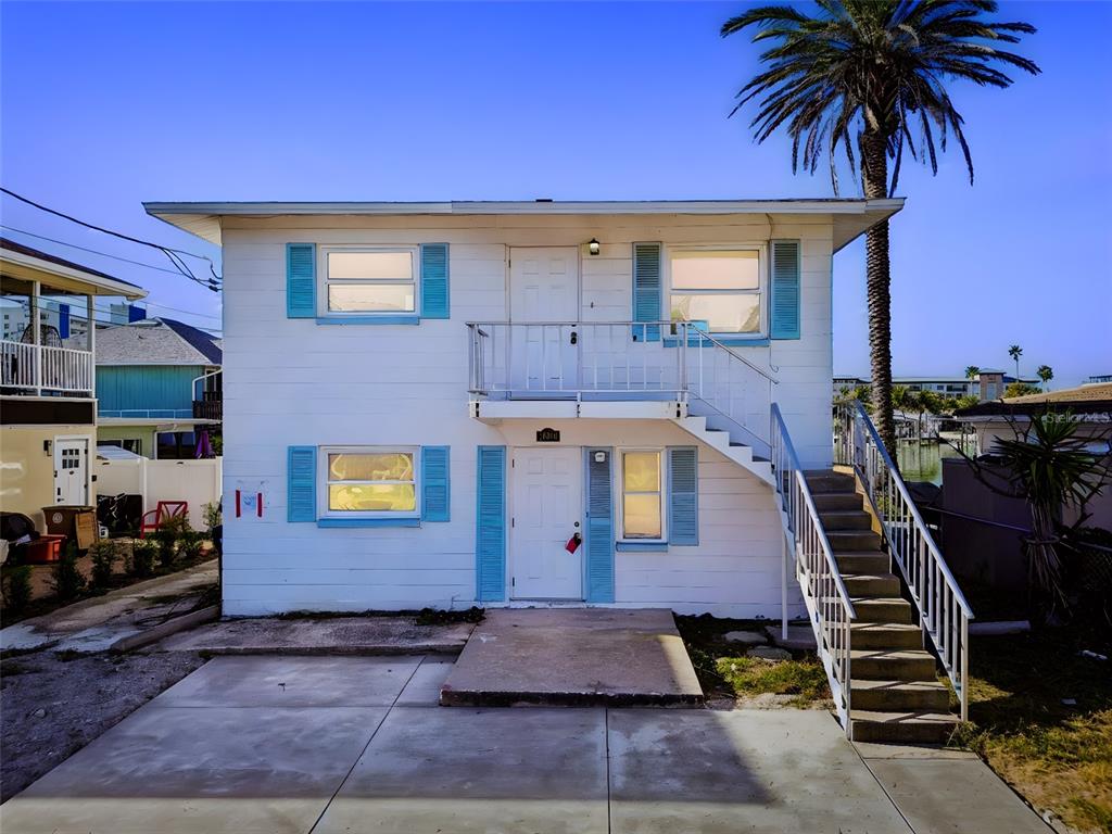 A two-story white house with blue shutters and an exterior staircase leading to the entrance — 14919 N BAYSHORE DRIVE UNIT 1, MADEIRA BEACH, FL