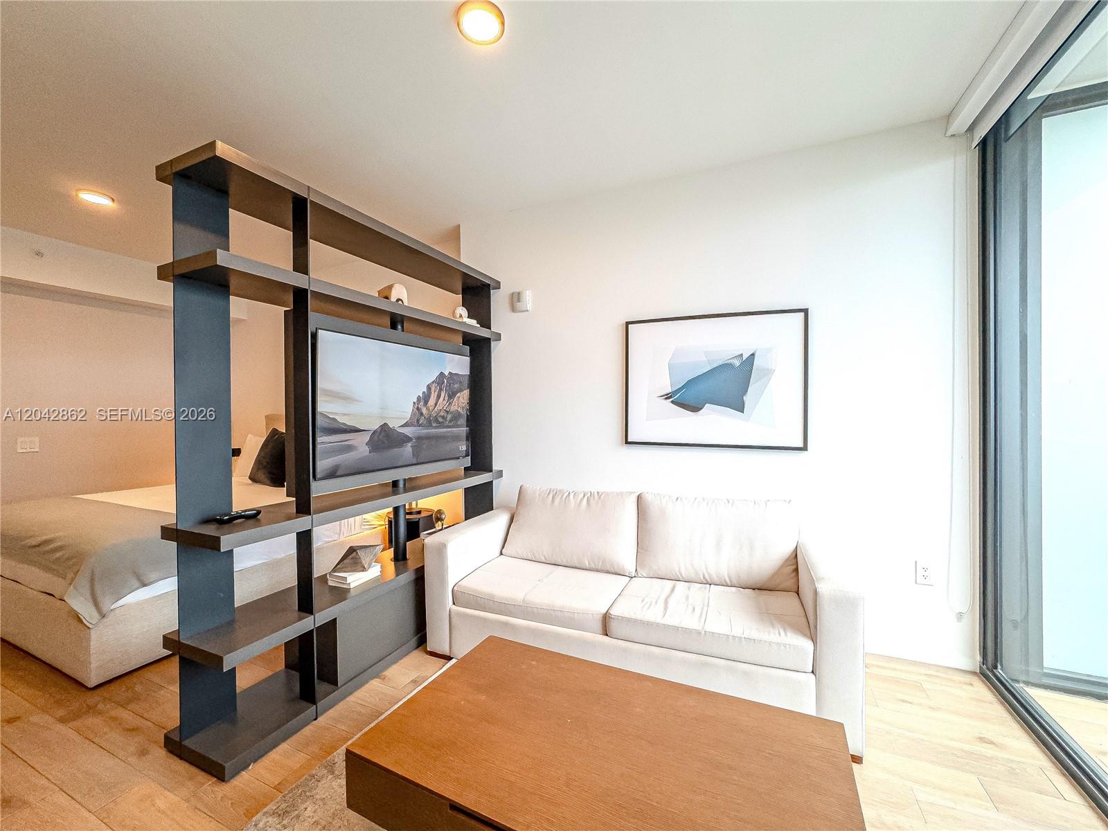 A living room features a sofa, coffee table, and a shelving unit with a television — 398 NE 5th St # 4316, Miami FL 33132, MIAMI, FL