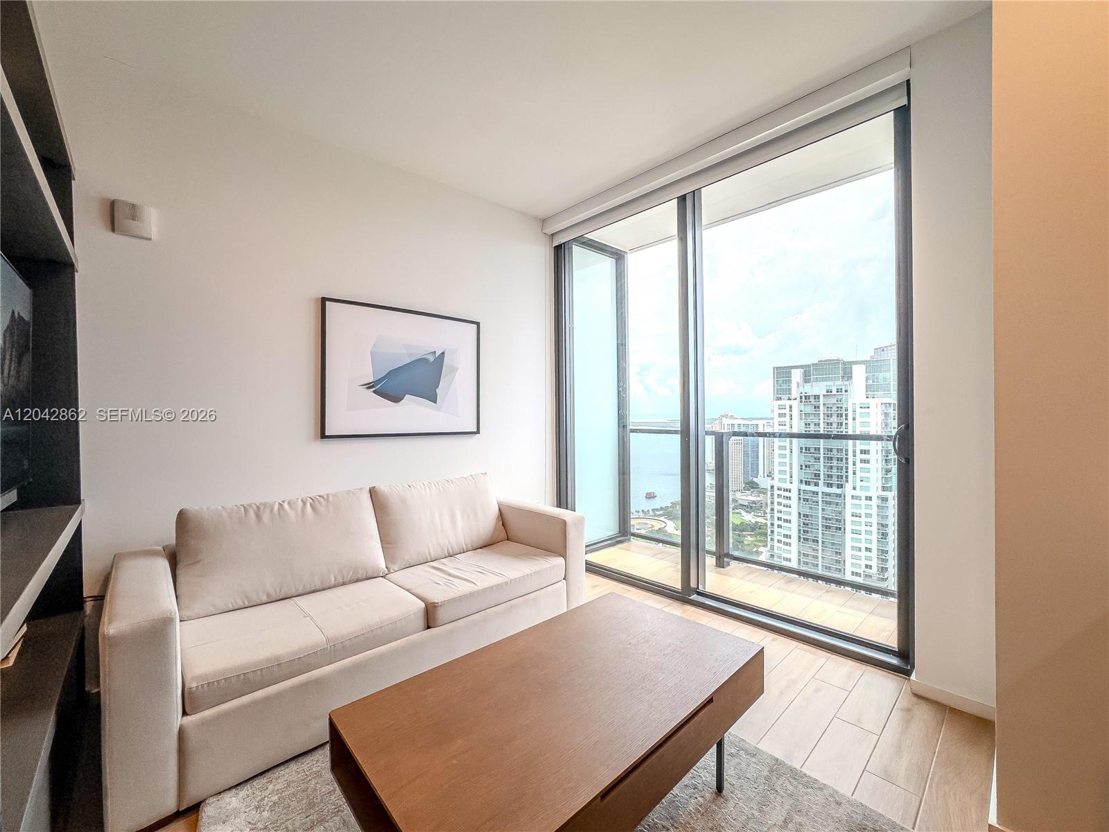 A living room features a beige sofa, wooden coffee table, and a balcony with city views — 398 NE 5th St # 4316, Miami FL 33132, MIAMI, FL
