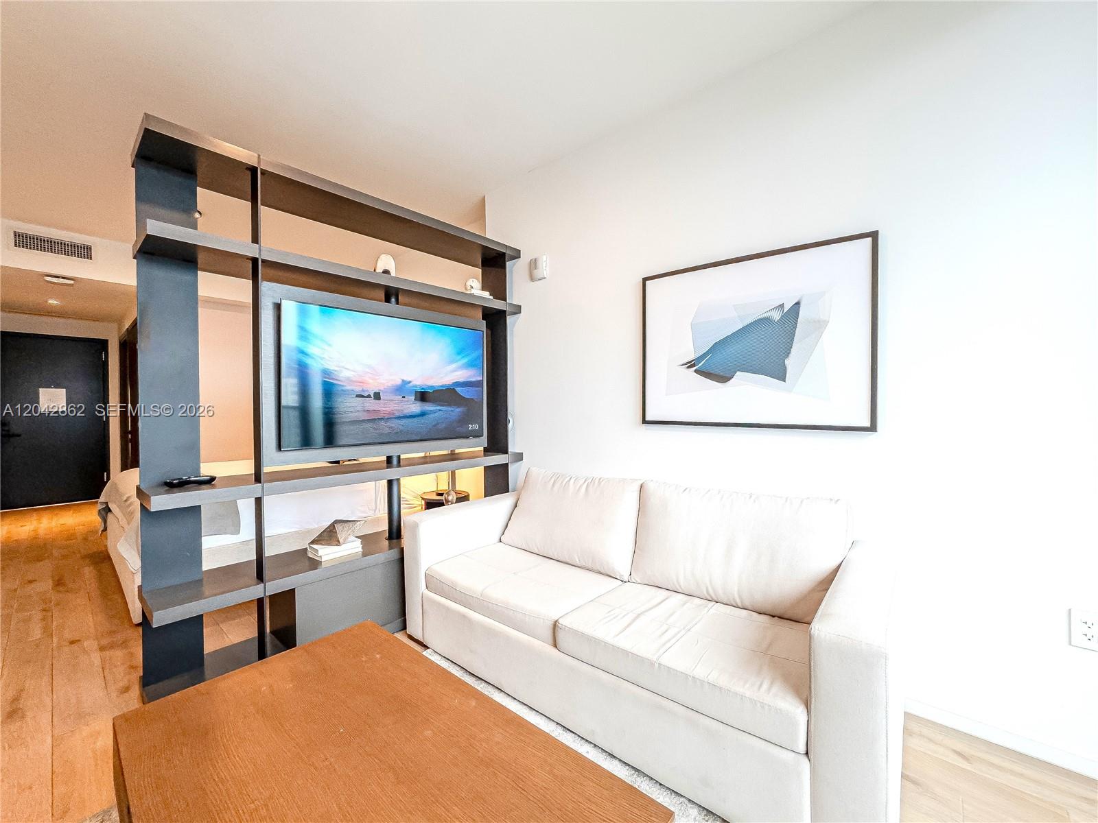 A living area features a light-colored sofa, a wooden coffee table, and a room-dividing shelving unit — 398 NE 5th St # 4316, Miami FL 33132, MIAMI, FL