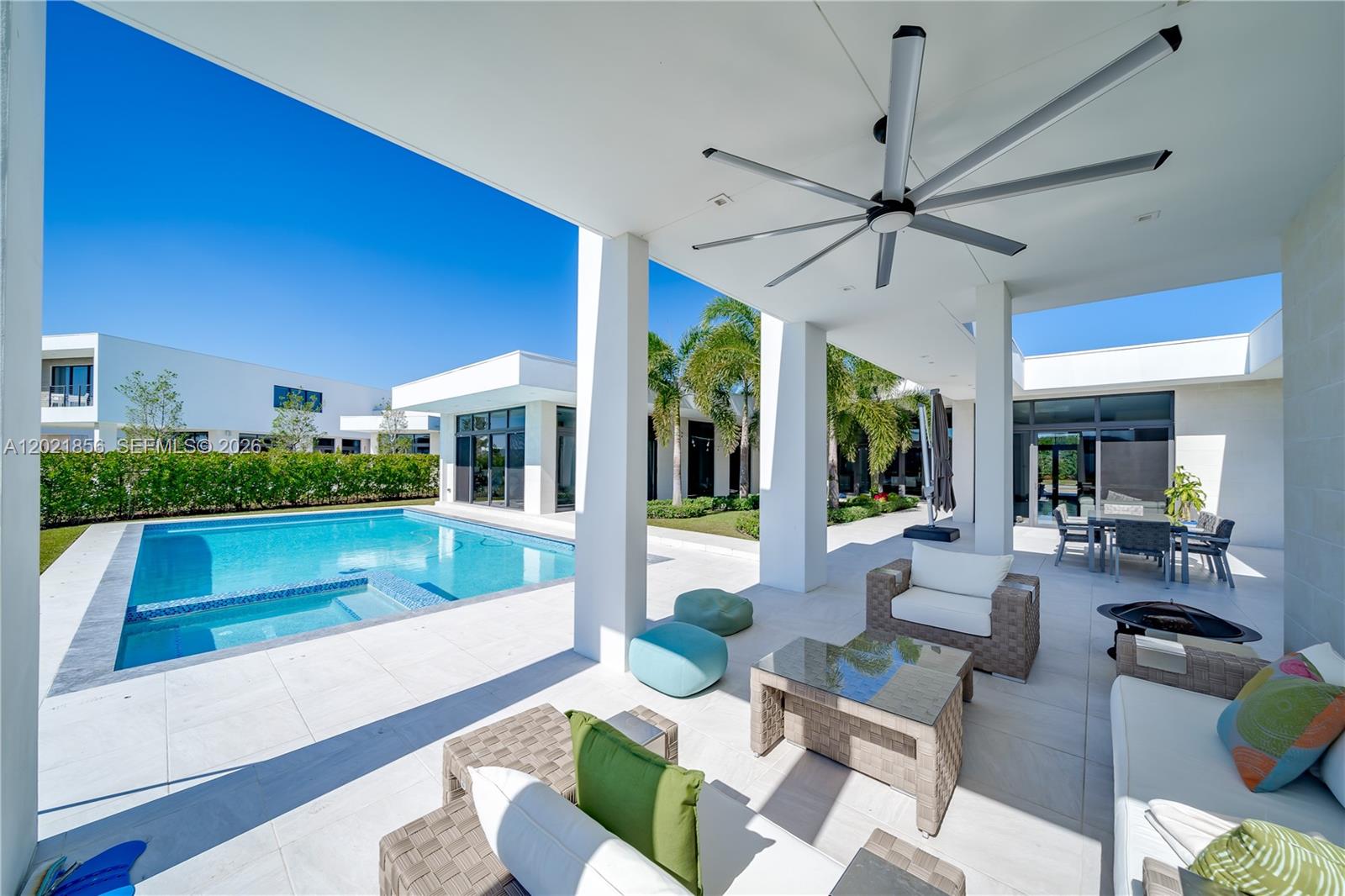 A modern house features a swimming pool and patio overlooking a lake under clear skies — 16600 Sunset Way, Weston FL 33326, WESTON, FL