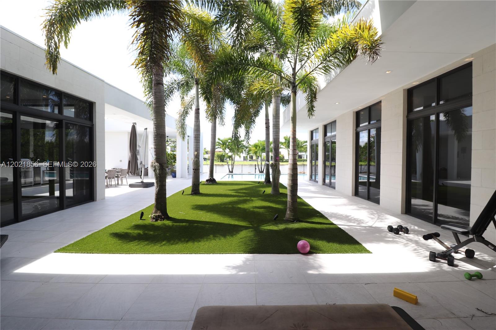 A modern single-story house with a flat roof, wood siding, and a paved driveway — 16600 Sunset Way, Weston FL 33326, WESTON, FL