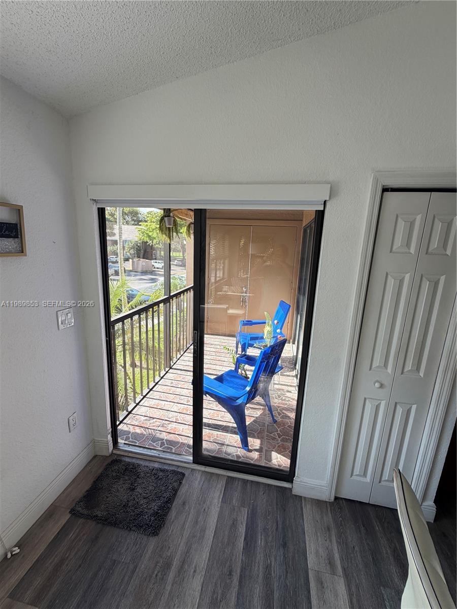 A room with wood-look flooring features a sliding glass door leading to a balcony — 10670 SW 156th Pl # 308, Miami FL 33196, MIAMI, FL