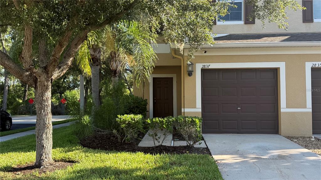 A tan house exterior features a brown garage door and a concrete driveway — 2837 SANTEGO BAY COURT, BRANDON, FL