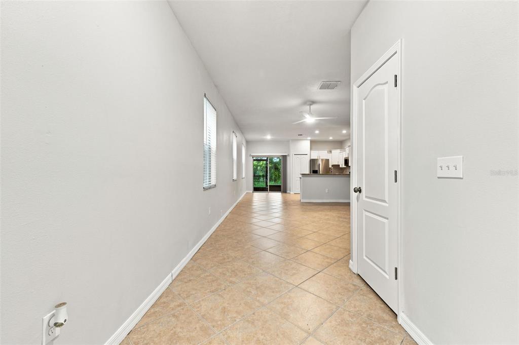A tiled hallway leads toward an open-concept kitchen and a glass door to the outdoors — 2837 SANTEGO BAY COURT, BRANDON, FL