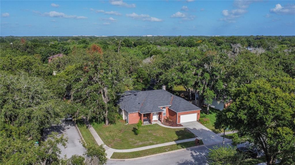 An aerial view of a single-story brick house with a dark shingled roof and driveway — 5443 BAYTOWNE PLACE, OVIEDO, FL