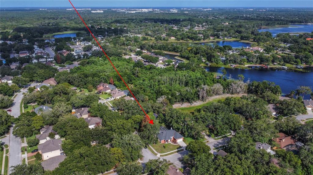 An aerial view shows a single-story house with a pool cage surrounded by dense trees — 5443 BAYTOWNE PLACE, OVIEDO, FL