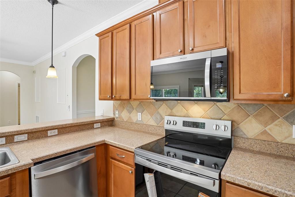 A kitchen features wood cabinets, stainless steel appliances, and a tan speckled countertop — 2331 CARNATION HILL COURT, ORLANDO, FL