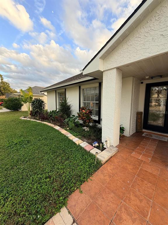A white house exterior features a tiled front porch, a landscaped garden, and a lawn — 15126 NIGHTHAWK DRIVE, TAMPA, FL