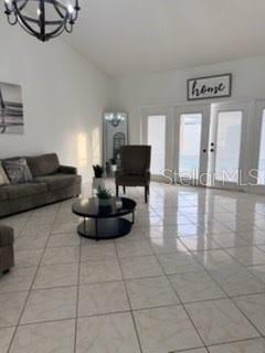 A living room features light tile flooring, a grey sofa, a round coffee table, and doors — 15126 NIGHTHAWK DRIVE, TAMPA, FL