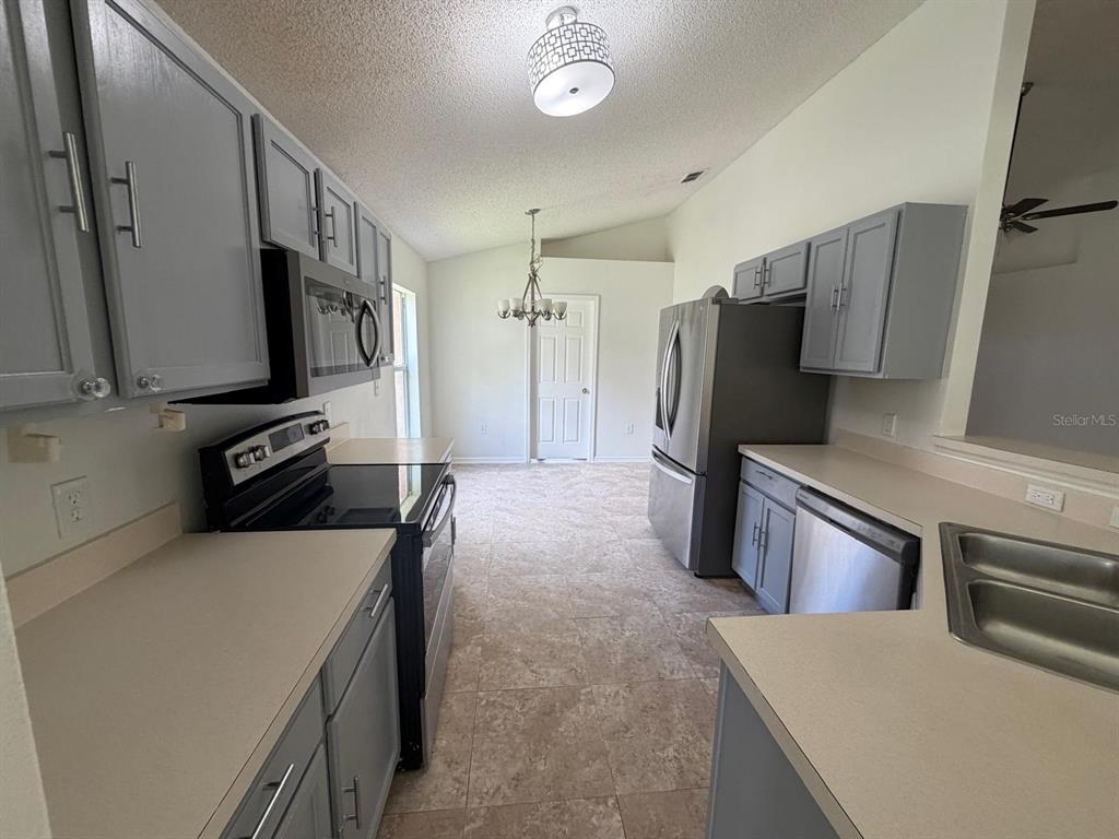 A kitchen features gray cabinets, stainless steel appliances, and light-colored countertops with tile flooring — 3015 ELBIB DRIVE, ST CLOUD, FL