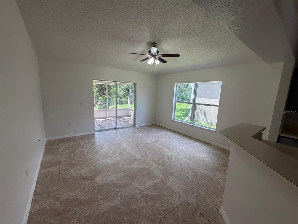 A living room with tile flooring, a ceiling fan, and a sliding glass door — 3015 ELBIB DRIVE, ST CLOUD, FL