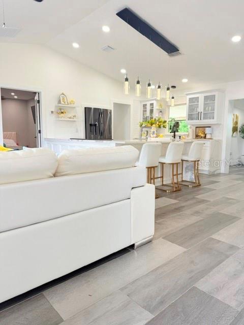 A white sofa sits in the foreground of an open-concept kitchen with pendant lighting — 608 JAGUAR COURT, POINCIANA, FL