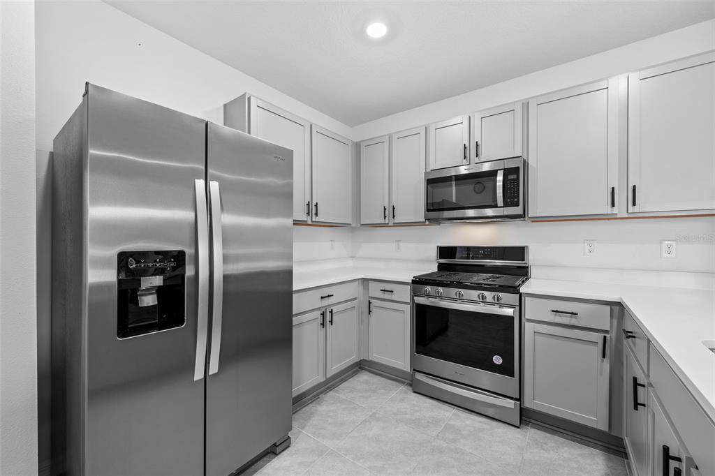 A kitchen features stainless steel appliances, light gray cabinets, and white countertops — 35630 KINSEY POINT, ZEPHYRHILLS, FL